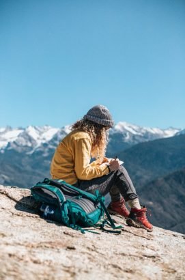 young-woman-writing-her-textbook-while-sitting-hill-near-mountain-683x1024-271x410